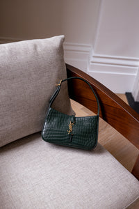 Saint Laurent Green Le 5 a 7 Shoulder Hobo Bag in croc leather placed on a chair. The Saint Laurent bag is available to rent